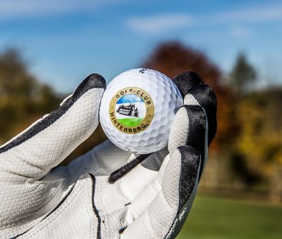 Golfer mit Handschuhen hält Golfball in den Händen