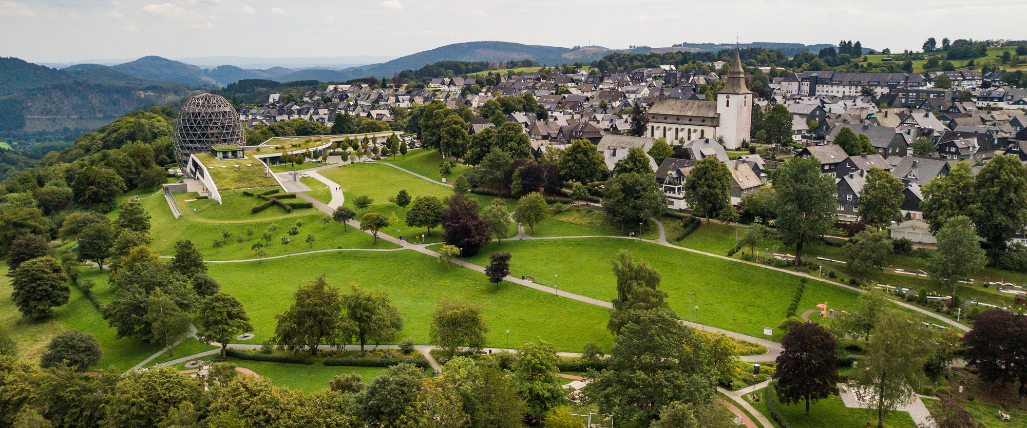 Drohnenaufnahme vom Kurpark Winterberg mit Blick auf einen Teil der Stadt und das Hotel Oversum.