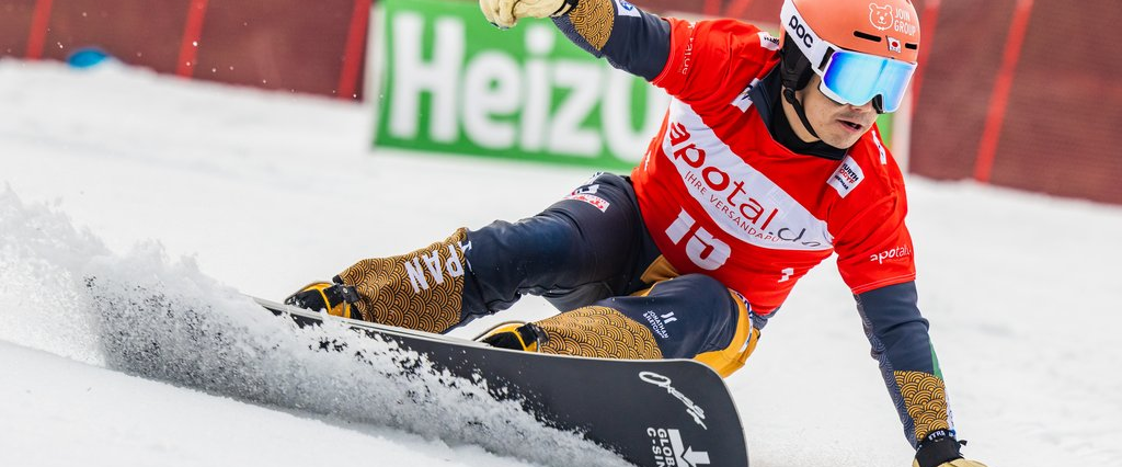 Ein Snowboardfahrer fährt mit seinem Snowboard einen Abhang hinunter.
