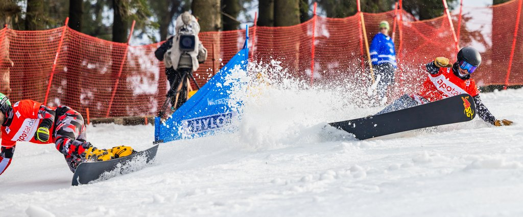 Zwei Snowboardfahrer, die sich bei der Abfahrt ordentlich in die Kurve legen.