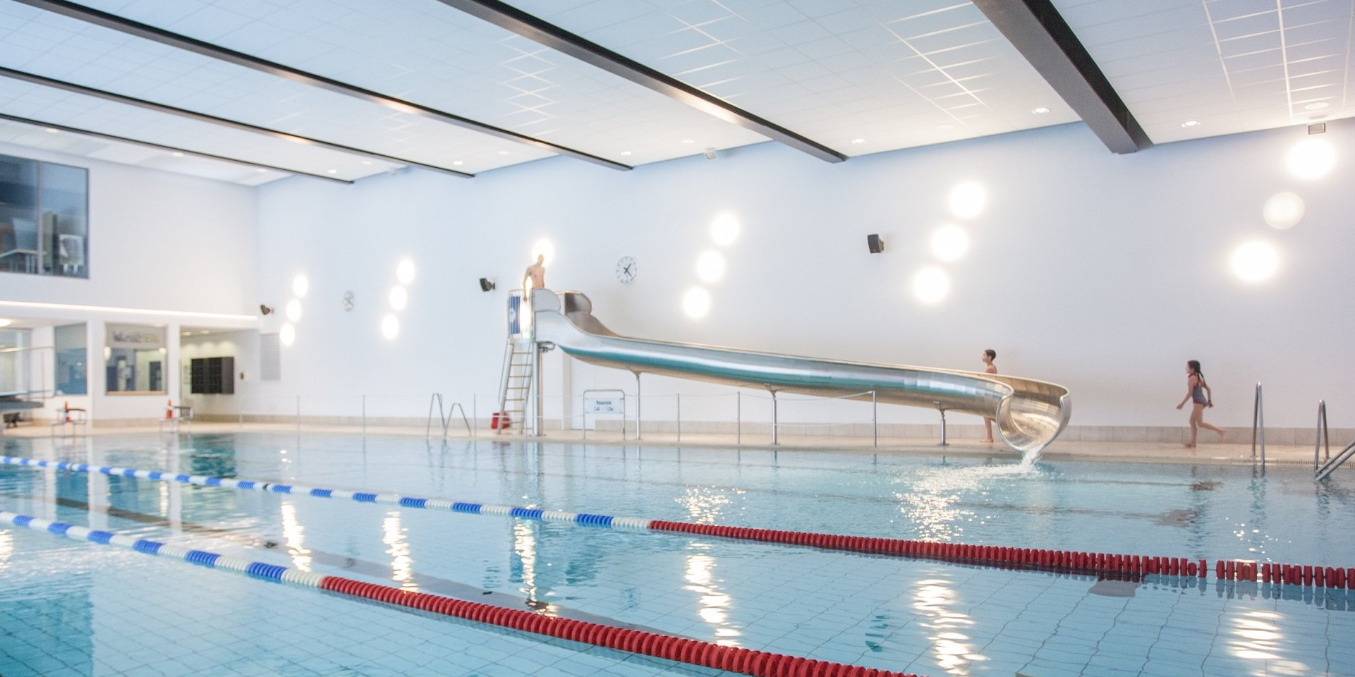 Das Sportbecken mit Wasserrutsche, Sprungbrett und Startblöcken im Schwimmbad Winterberg.