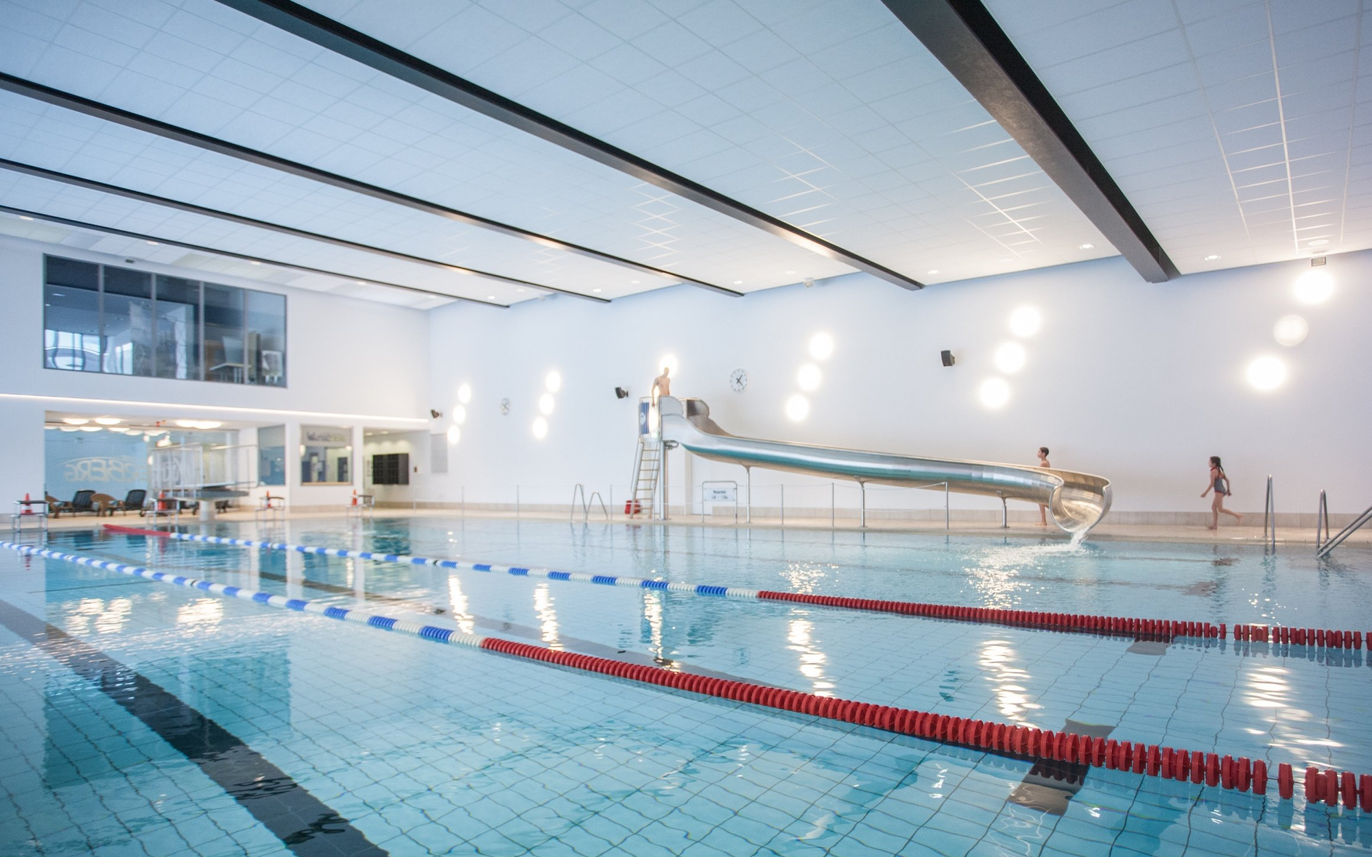 Das Sportbecken mit Wasserrutsche, Sprungbrett und Startblöcken im Schwimmbad Winterberg.