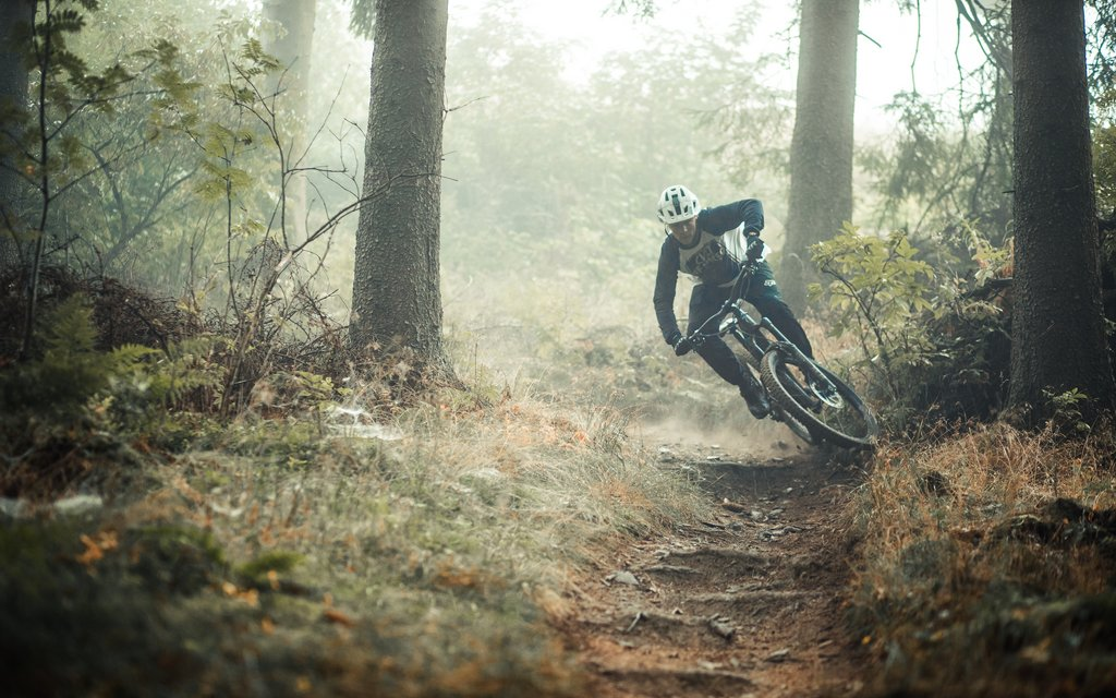 Ein Mann fährt mit seinem Mountainbike auf einem Trail des Trailparks durch eine scharfe Kurve