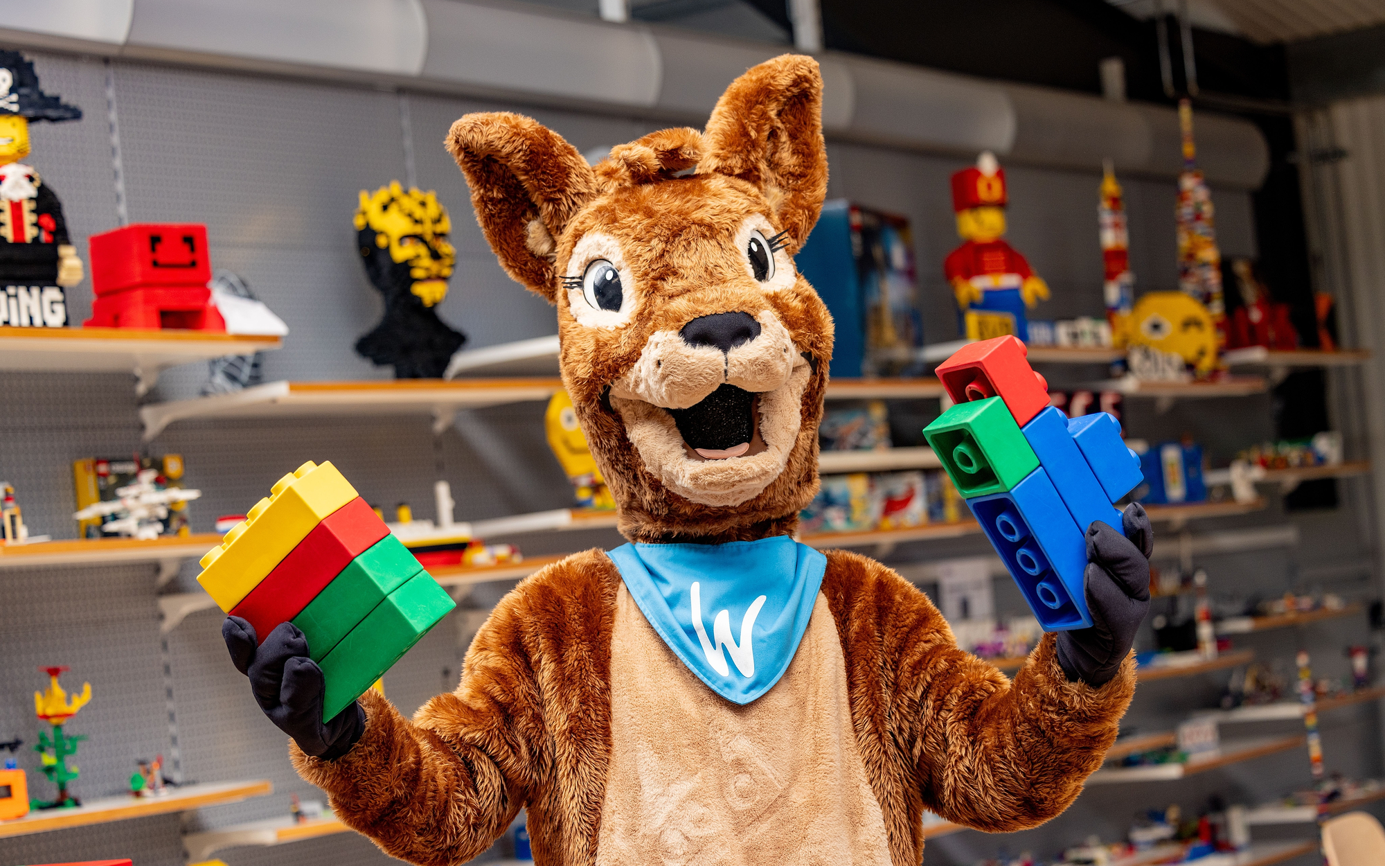 Das Maskottchen der Ferienwelt Winterberg, Reh Waldi, mit großen Legosteinen in den Händen.