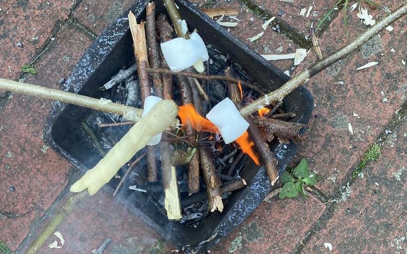 Stockbrot und Marshmallows werden an einem kleinen Grill zubereitet