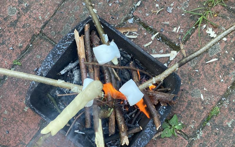 Stockbrot und Marshmallows werden an einem kleinen Grill zubereitet