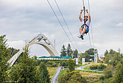 Ein Mann fliegt die Zipline an der Sprungschanze hinunter.