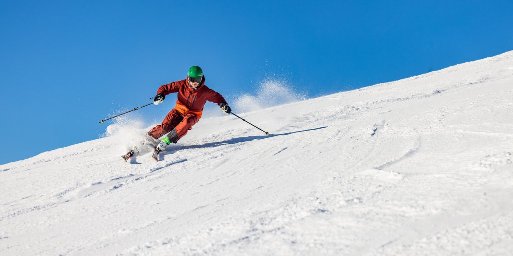 Skifahrer fährt bei Sonnenschein eine Piste im Skiliftkarussell Winterberg hinunter.