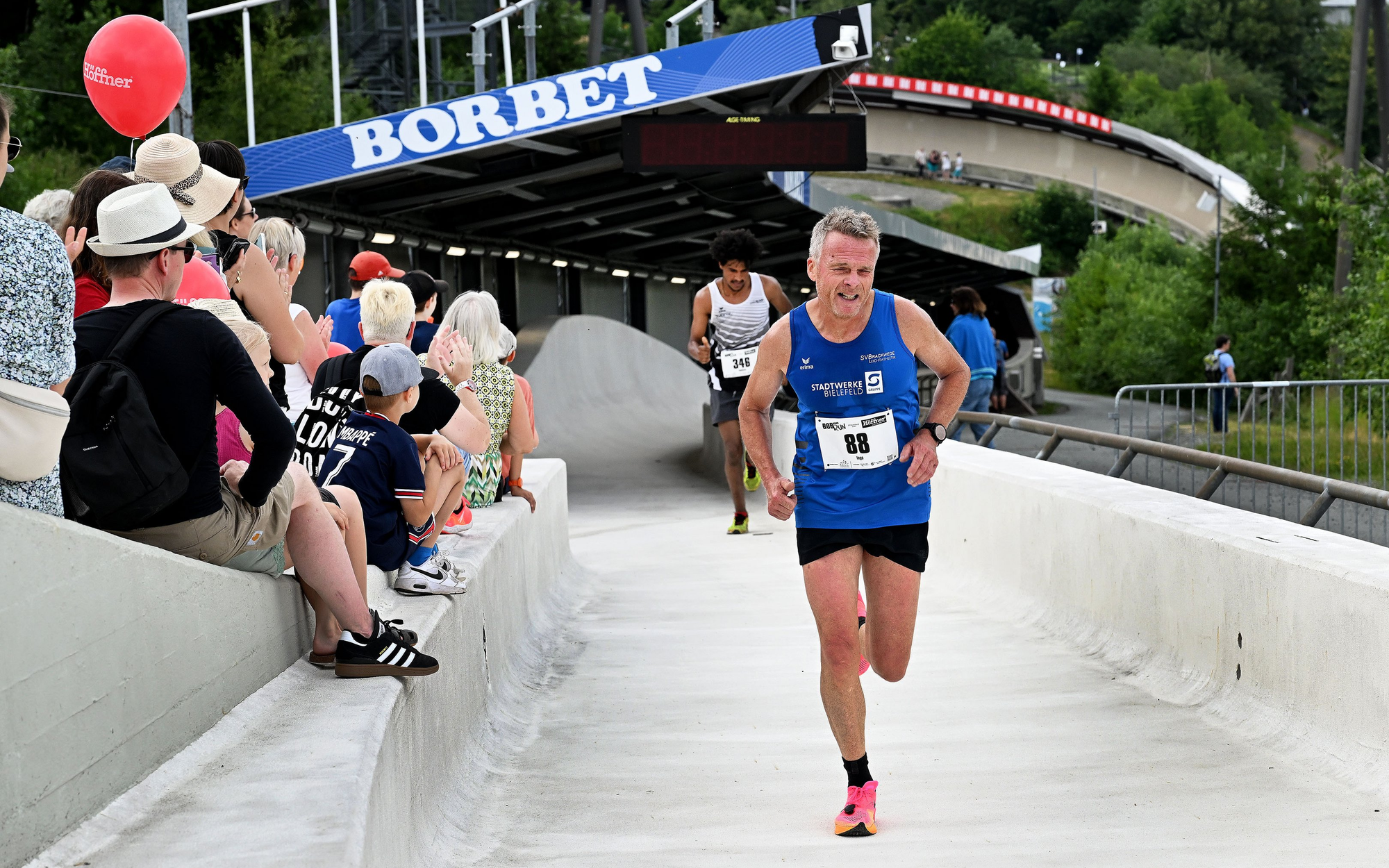 Zwei Sportler beim Bobbahnrun in der Veltins Eisarena laufen durch den Eiskanal.
