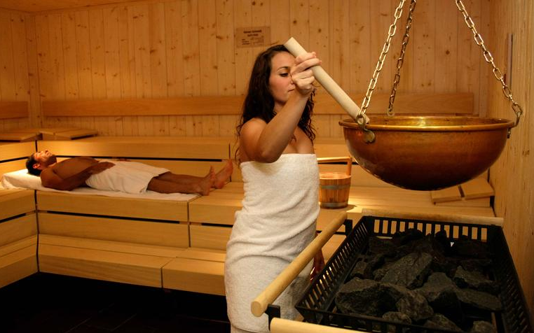 Eine Frau und ein Mann in der Sauna beim Saunaaufguss.