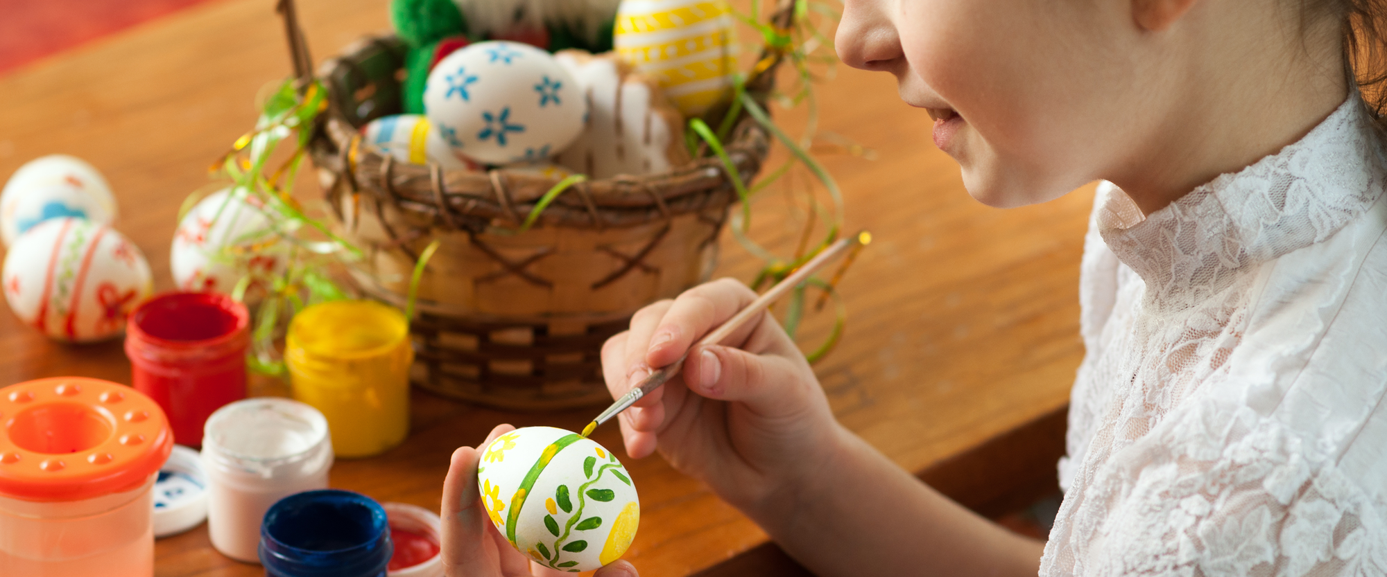 Ein Mädchen bemalt bunte Ostereier