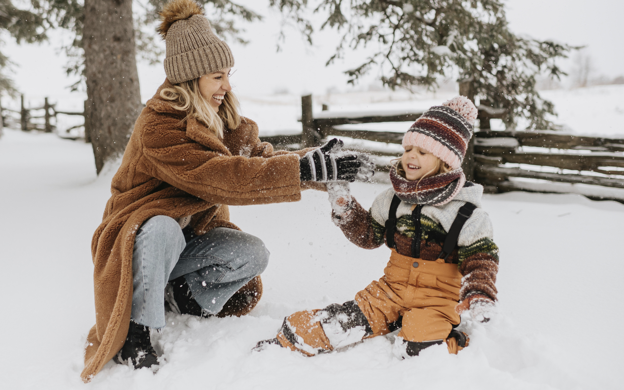 Eine Mutter spielt mit ihrem Kind im Schnee.