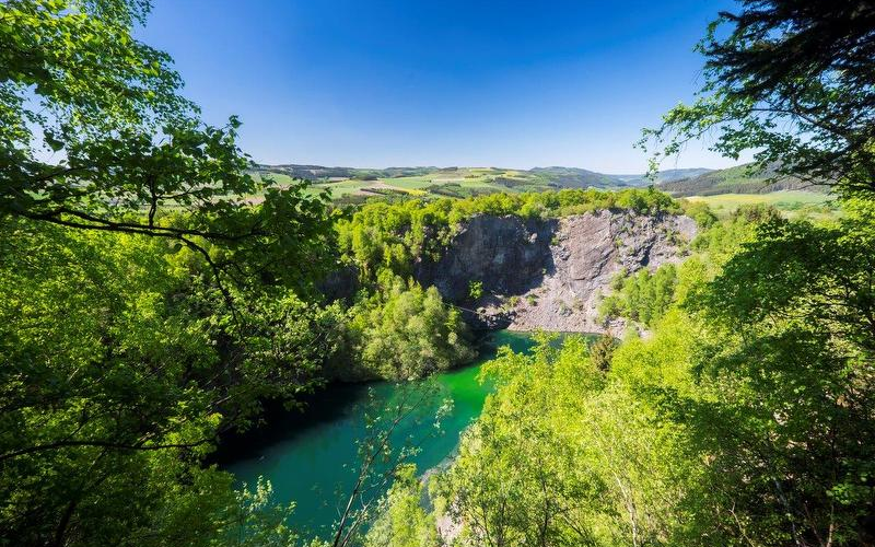Ein Bergsee umgeben von Felsen und Wald.