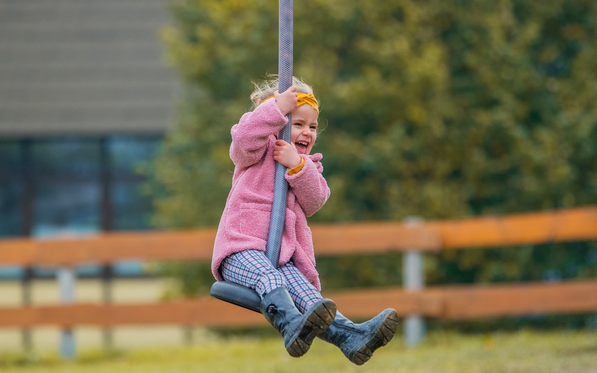 Kleines Mädchen lachend auf einer Seilrutsche auf dem Spielplatz