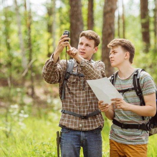Zwei junge Männer im Wald beim Geocaching