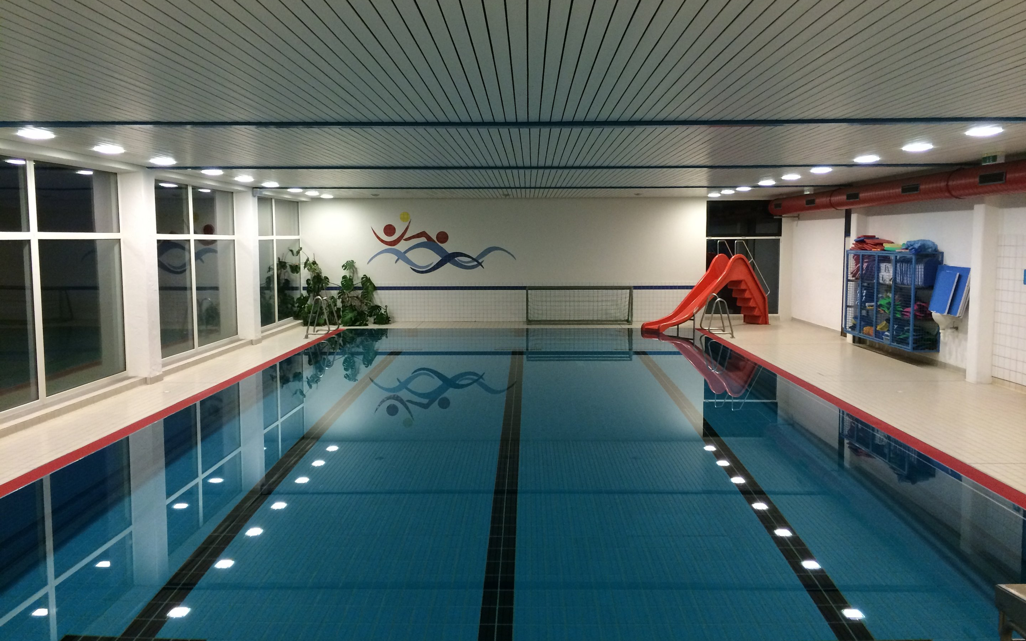 Das Sportbecken im Hallenbad von Siedlinghausen mit einer roten Wasserrutsche.