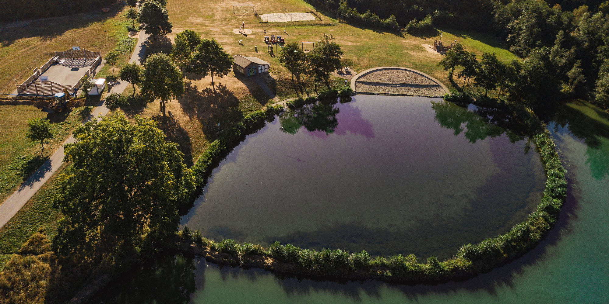 Der Hillebachsee mit Spielplatz, Volleyballfeld und Basketballfeld aus der Vogelperspektive.