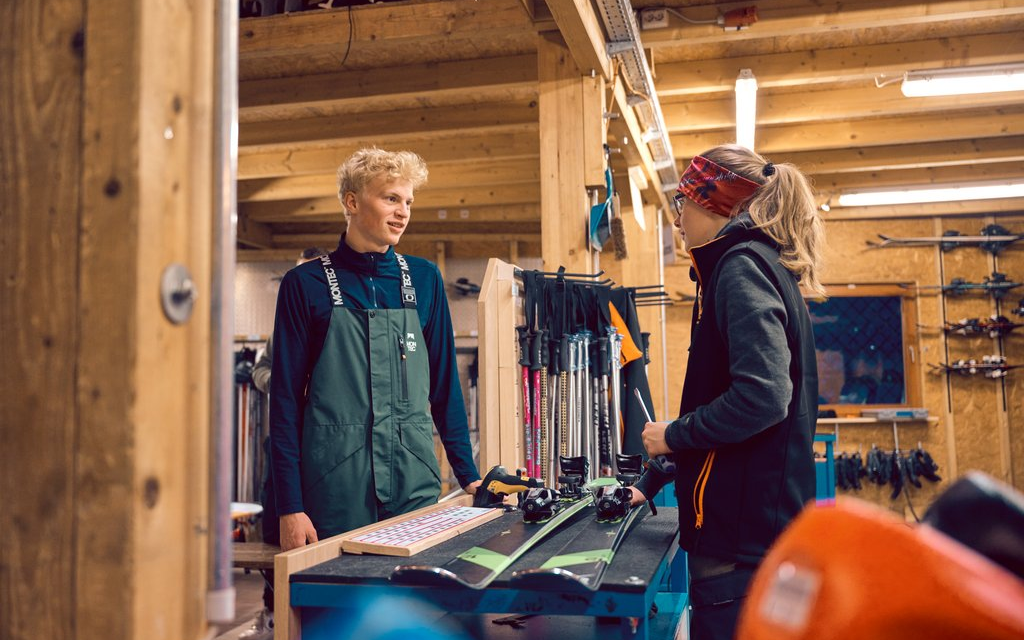 Ein junger Mann berät eine Frau im Skiverleih.