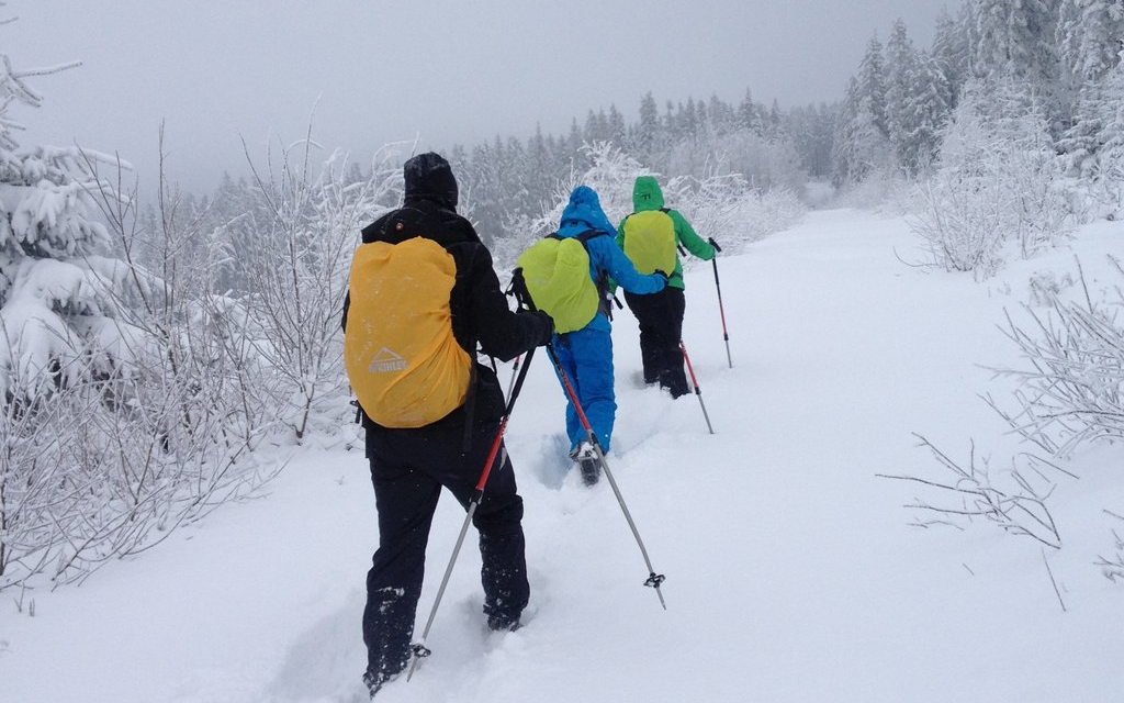 Drei Personen machen eine Wanderung durch Tiefschnee.