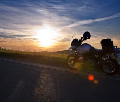 Ein Motorrad steht auf einem Weg, dahinter der Sonnenuntergang