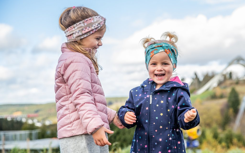 Zwei Kinder stehen im Vordergrund der St. Georg Sprungschanze in Winterberg.